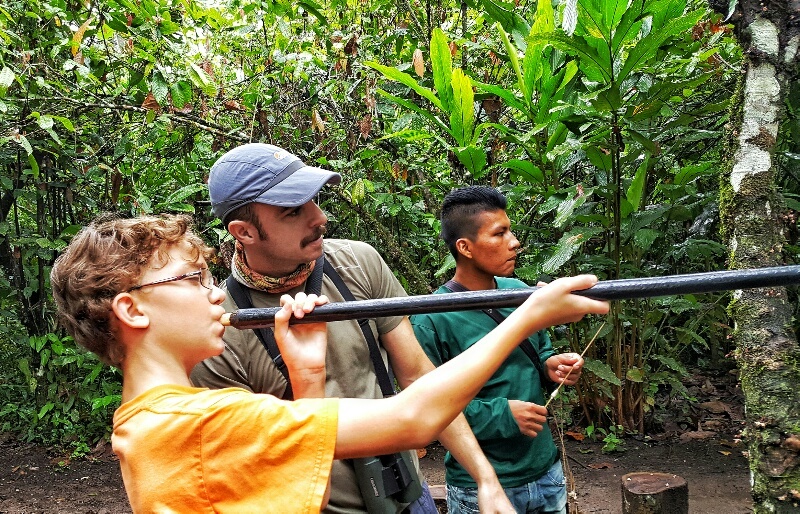 Boy learning to shoot a blow dart in the Ecuadorian Amazon