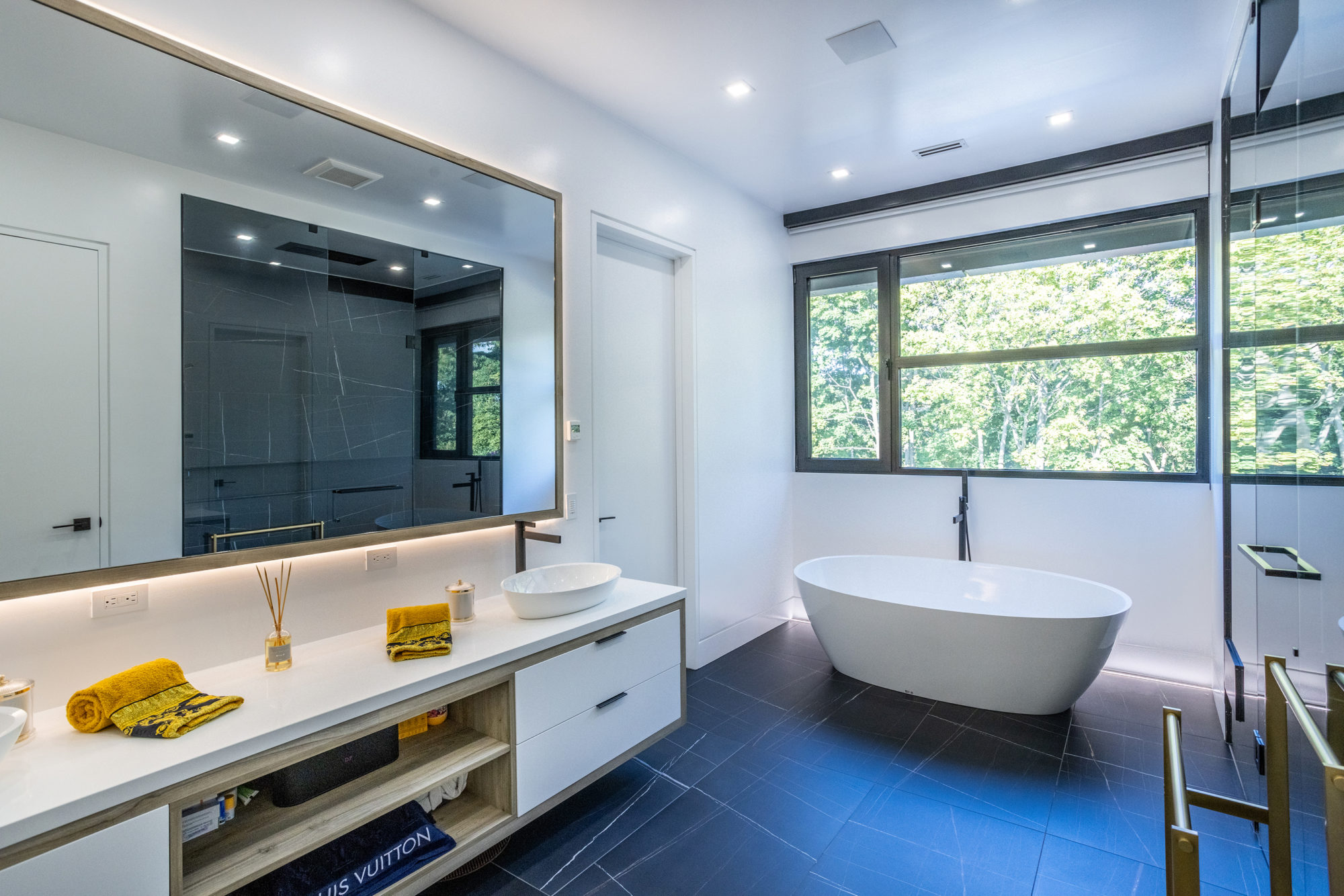 The main ensuite has a super-wide vanity, a jumbo mirror, a soaker tub and a glass shower. 