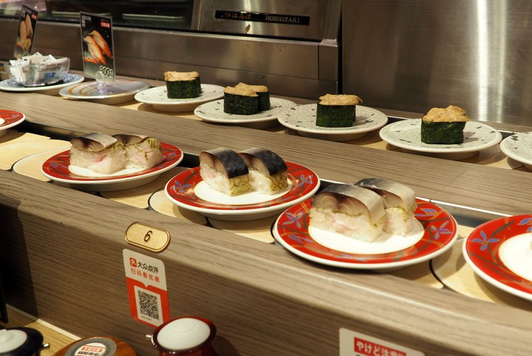 conveyor belt sushi restaurant in Kyoto Japan, nigiri sushi plates pass by the table