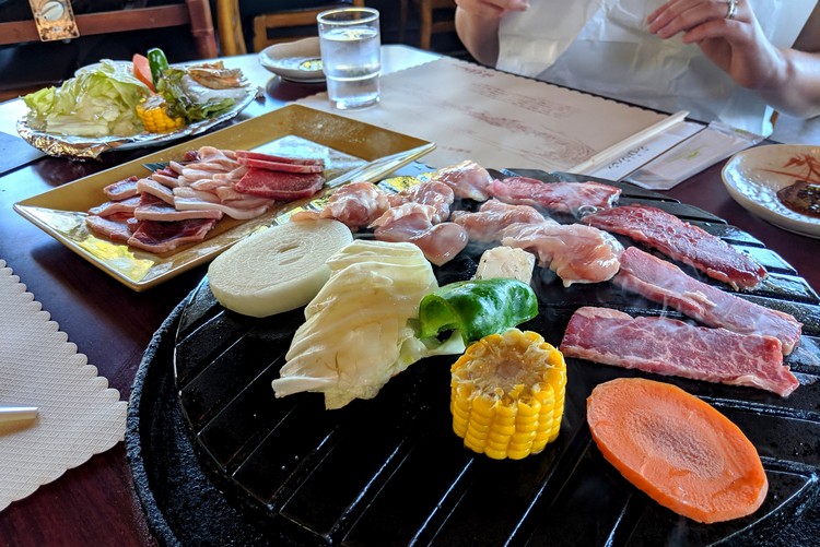 Grilling meat and vegetables at Rokkosan Genghis Khan Palace restaurant on Mount Rokko in Kobe, Japan