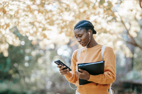 A student is listening to music using smartphone in park.